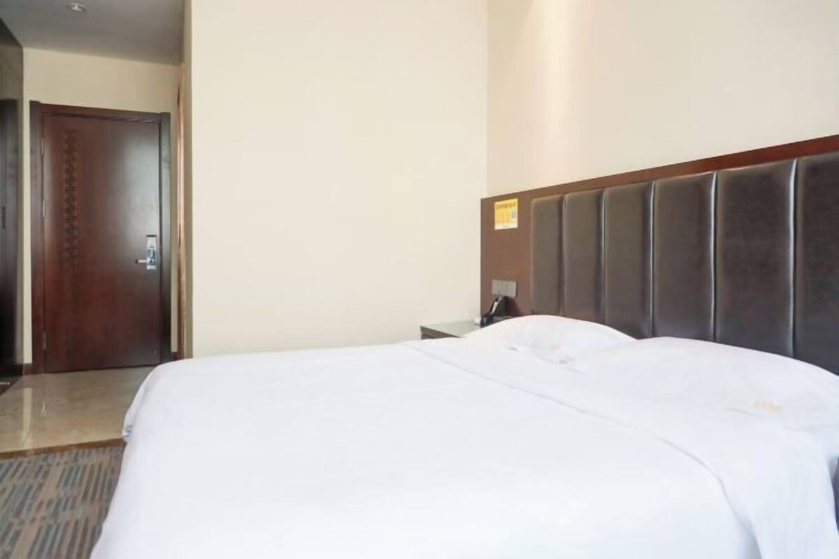 Une chambre d’hôtel avec un grand lit, une porte en bois et une table de chevet avec une lampe.