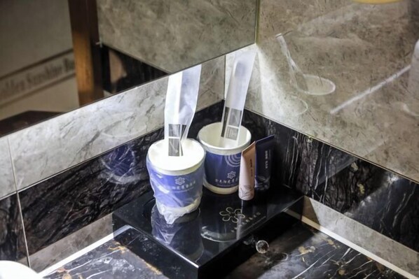 Une salle de bain dotée d’un comptoir en marbre, de deux distributeurs d’essuie-tout et d’un distributeur de savon.