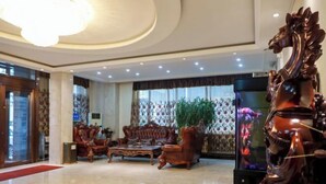 A lobby with a large chandelier, a wooden statue, and a television screen.