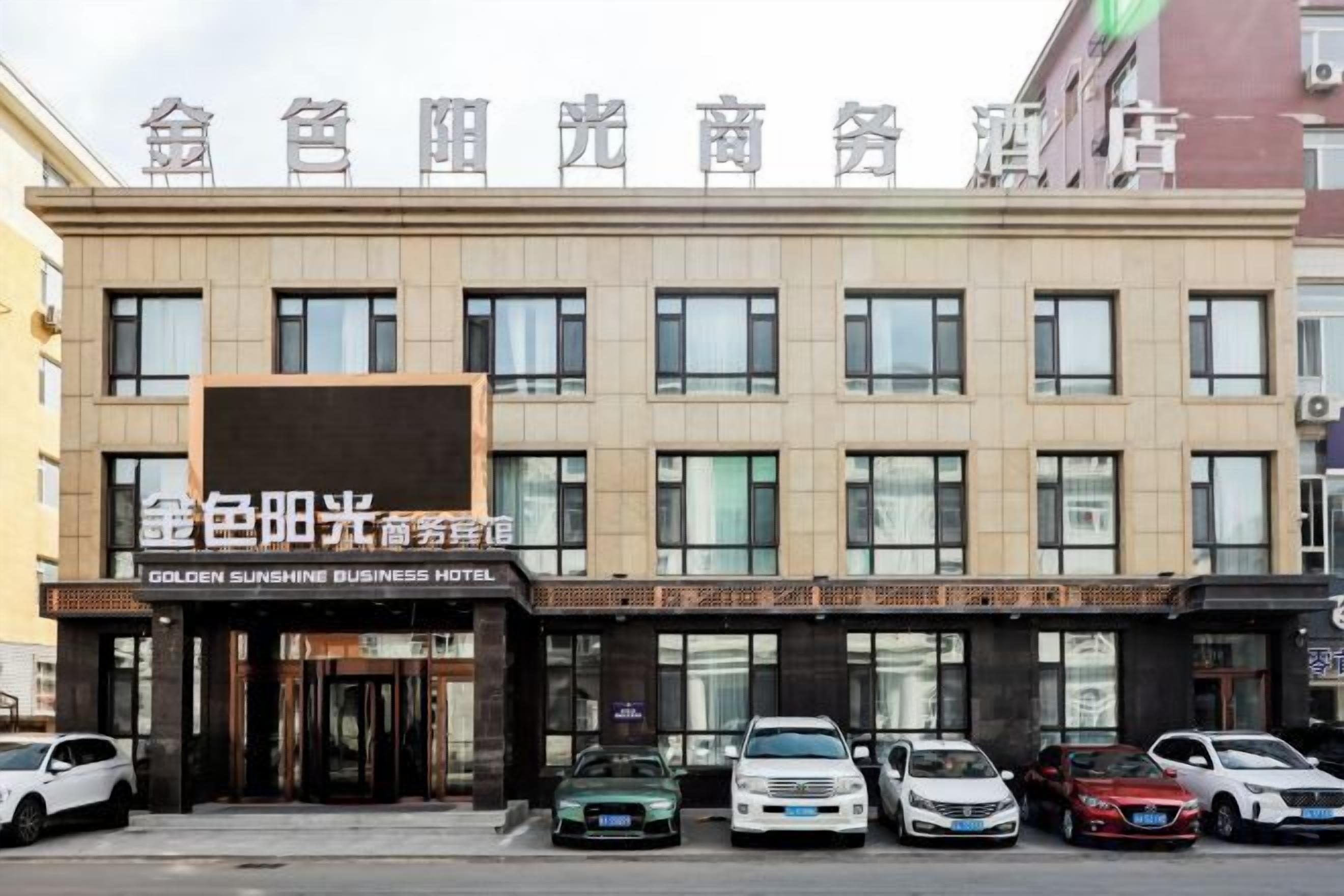 A hotel with a sign reading 'GOLDEN SUNSHINE BUSINESS HOTEL' and multiple cars parked in front.