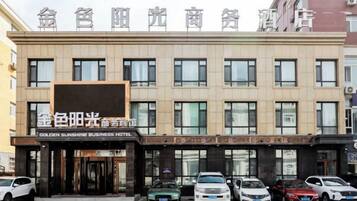A hotel with a sign reading 'GOLDEN SUNSHINE BUSINESS HOTEL' and multiple cars parked in front.