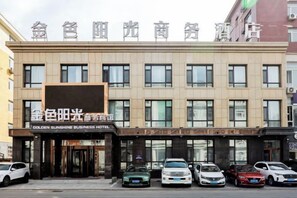 A hotel with a sign reading 'GOLDEN SUNSHINE BUSINESS HOTEL' and multiple cars parked in front.