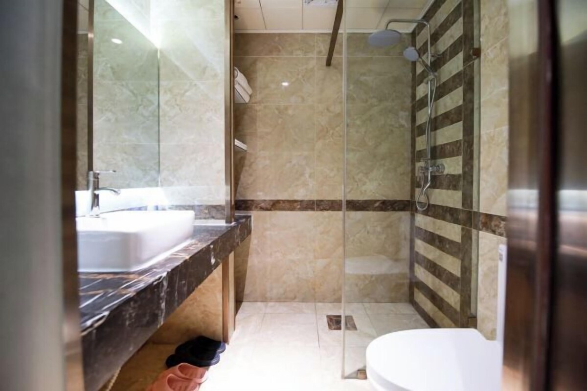 A bathroom with a glass shower enclosure, a sink, and a toilet.