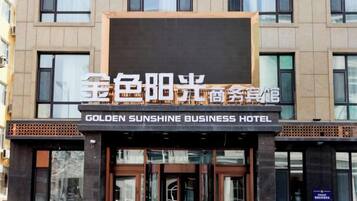 A hotel facade with a sign indicating 'GOLDEN SUNSHINE BUSINESS HOTEL'.