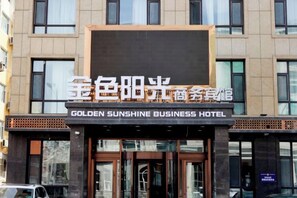 Fachada de hotel con un cartel que indica 'GOLDEN SUNSHINE BUSINESS HOTEL'.