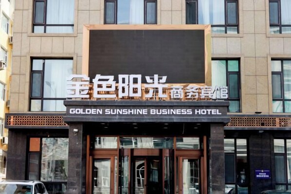 En hotelfacade med et skilt, der viser 'GOLDEN SUNSHINE BUSINESS HOTEL'.
