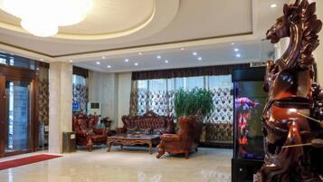 A lobby with a chandelier, a large sofa set, and a decorative horse statue.