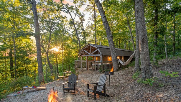 A cabin with a fire pit and Adirondack chairs in a forest setting. - Hot Tub! Tiny House Retreat in the Woods (Stanton)
