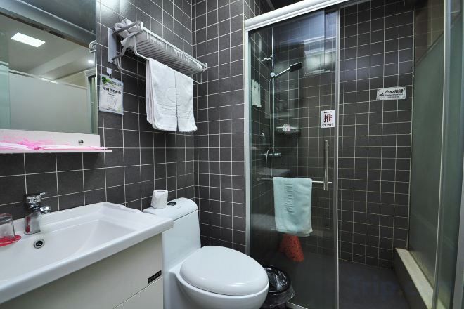 Un baño con lavamanos blanco, inodoro y cabina de ducha con mampara de vidrio.