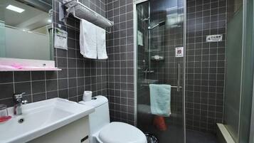 Un baño con lavamanos blanco, inodoro y cabina de ducha con mampara de vidrio.