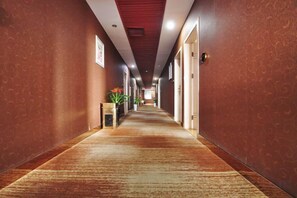 A hotel hallway with a carpeted floor, doors on both sides, and a plant on the left. - Dushi 118 Chain Hotel (Ningbo Yuyao High‑speed Railway North Station Branch) (Yuyao)