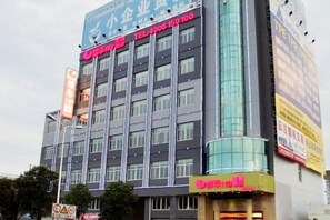 A multi-story building with a prominent sign for a hotel on the ground floor. - Dushi 118 Chain Hotel (Ningbo Yuyao High‑speed Railway North Station Branch) (Yuyao)