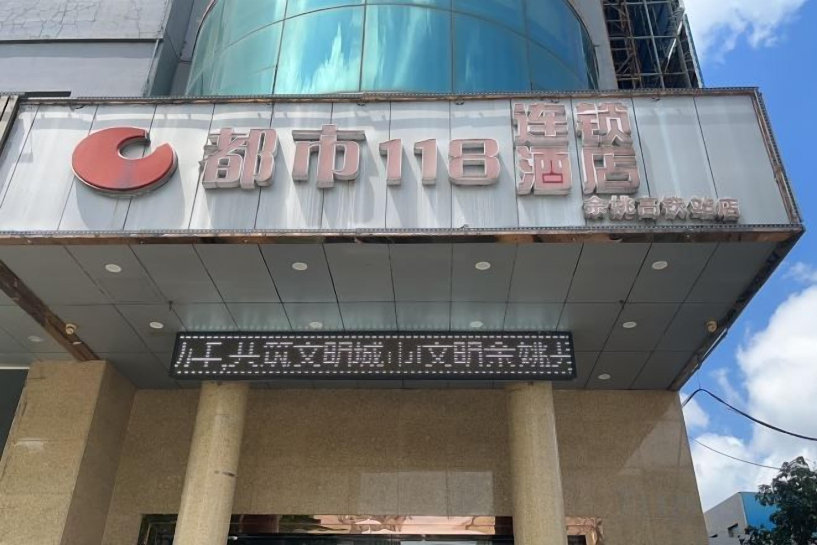 Señal de hotel con un logotipo destacado y el nombre '都市118宿舍'.
