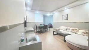 A modern living room with a sofa, a coffee table, a TV mounted on the wall, and a dining area with chairs and a table. - Dushi 118 Chain Hotel (Ningbo Yuyao High‑speed Railway North Station Branch) (Yuyao)