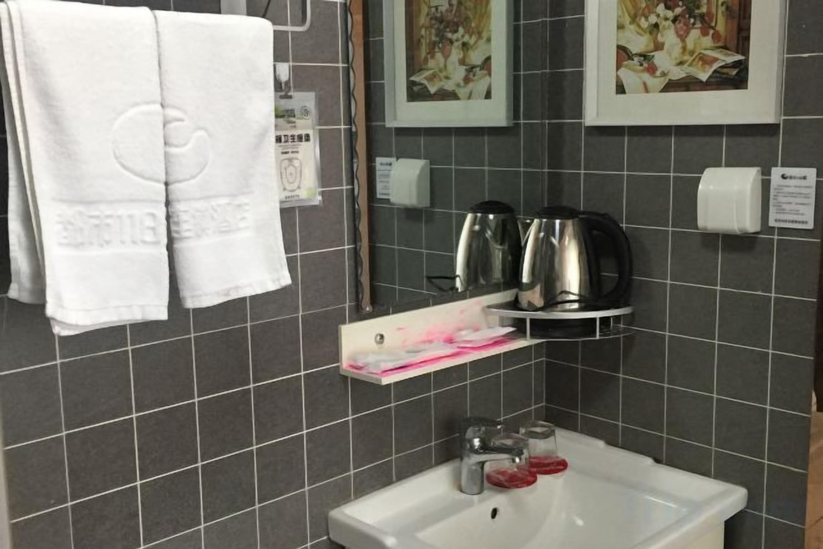 A bathroom with a sink, two towels, a soap dispenser, and a coffee maker.