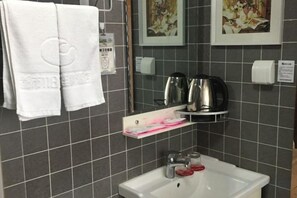 A bathroom with a sink, two towels, a soap dispenser, and a coffee maker. - Dushi 118 Chain Hotel (Ningbo Yuyao High‑speed Railway North Station Branch) (Yuyao)
