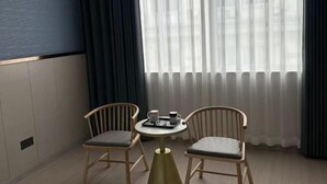 A room with a round table, two chairs, a window with sheer curtains, and a dark blue wall. - Dushi 118 Chain Hotel (Ningbo Yuyao High‑speed Railway North Station Branch) (Yuyao)