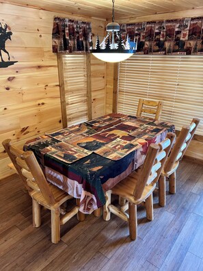 Una mesa de comedor de madera con mantel acolchado, rodeada de sillas de madera.