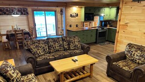 Interior acogedor de una cabaña con sofá, sillón y una mesa de centro de madera.