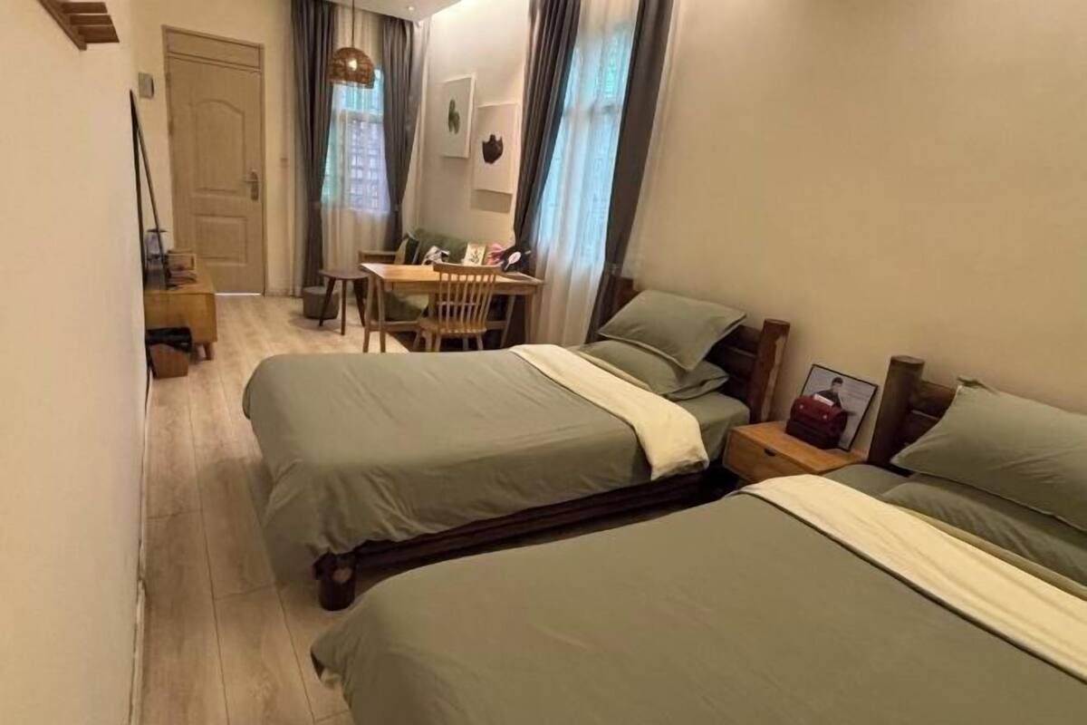 A hotel room with two beds, a small table, and a chair.