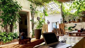 A laptop on a table in a room with plants and a wooden bench. - Me Town House (Shenzhen)