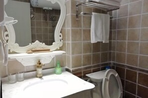 Un bagno con un lavandino bianco, uno specchio con cornice decorata, un portascopevoli e un water.