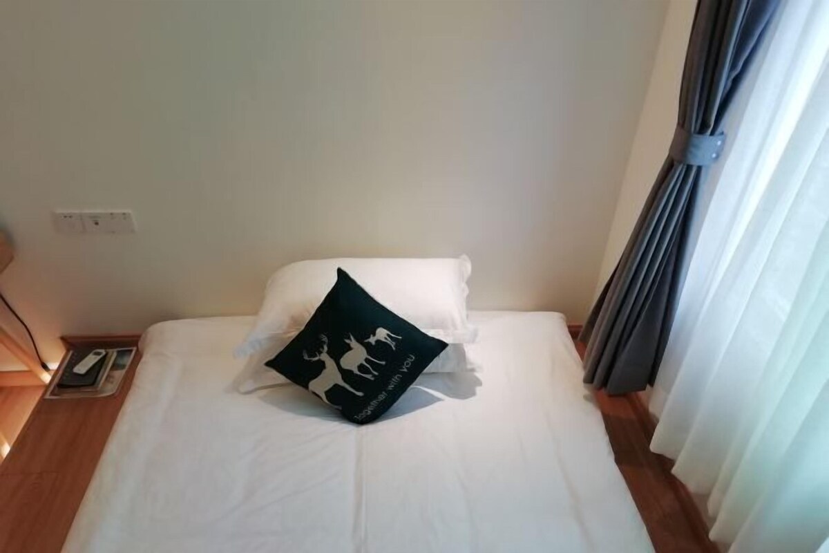 Ein ordentlich bezogenes Bett mit weißer Bettwäsche und einem einzelnen Zierkissen mit Tierstempeln.