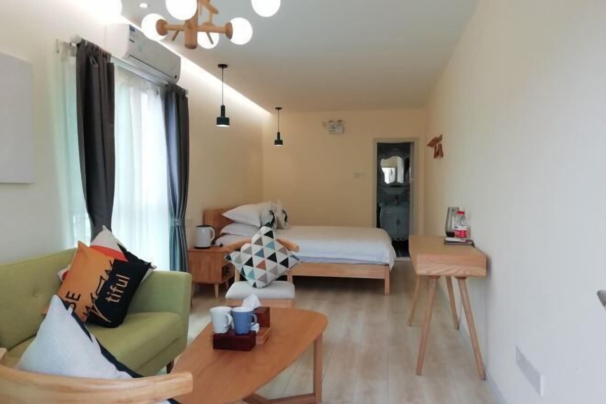 Ein kompaktes Hotelzimmer mit Bett, Sofa, kleinem Tisch und Schreibtisch.