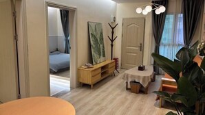 A modern living room with a wooden floor, a round table, a sofa, and a large plant. - Me Town House (Shenzhen)