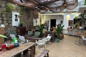 Un espace patio intérieur avec des murs en pierre, des meubles en bois et des plantes en pot.
