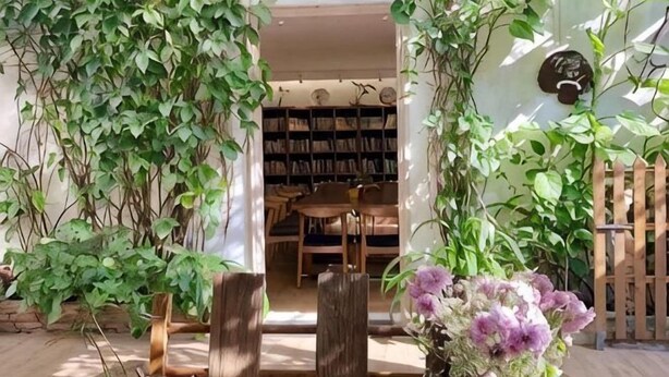An entrance with a wooden gate, a wooden table, and a bookshelf in the background. - Me Town House (Shenzhen)