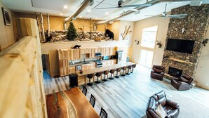 A spacious living area with a stone fireplace, a wooden bar, and a cozy seating area. - The Lodge at Nature Shores (Pine City)