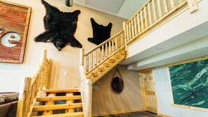 A wooden staircase with a handrail, a black leather wall hanging, and a wooden door. - The Lodge at Nature Shores (Pine City)