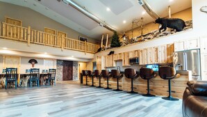 A spacious indoor area with a long wooden bench, a high ceiling, and a bear statue on the wall. - The Lodge at Nature Shores (Pine City)