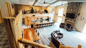 A spacious living area with a stone fireplace, leather sofas, and a wooden entertainment center. - The Lodge at Nature Shores (Pine City)