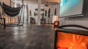 Una sala de estar moderna con chimenea, una hamaca y una pantalla grande mostrando servicios de streaming.