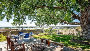 Patio trasero con un hogar, mobiliario exterior y vista a un lago.