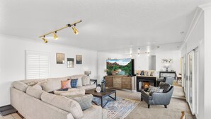 A living room with a beige sofa, a gray armchair, a coffee table, and a fireplace. - St George Vacation Rental| Condo sleeps 8 guest with Resort Amenities (St. George)