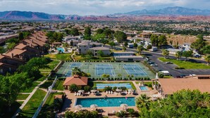 A residential area with a large swimming pool, tennis courts, and a mountain backdrop. - St George Vacation Rental| Condo sleeps 8 guest with Resort Amenities (St. George)