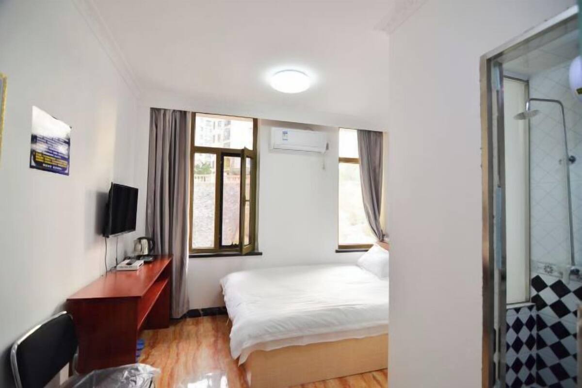 Una habitación de hotel con cama, escritorio, televisor y ducha.