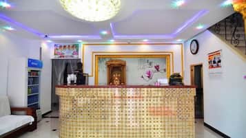 A reception area with a tiled counter, a chandelier, and a clock on the wall.