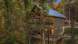 Eine zweistöckige Hütte mit Balkon, umgeben von einem Wald.