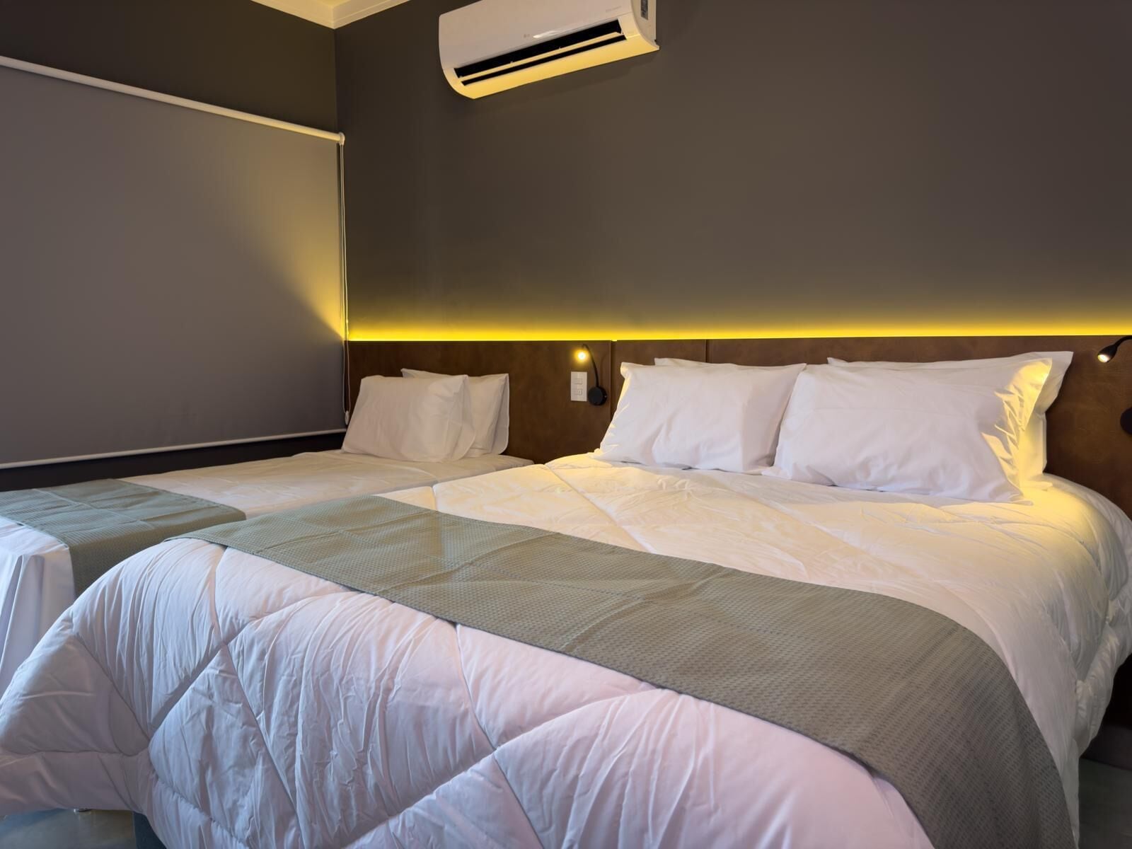 Une chambre d’hôtel avec un grand lit, une table de chevet et un climatiseur fixé au mur.