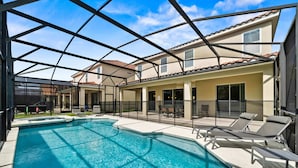A swimming pool with lounge chairs and a covered patio area. - 4x TV Wall, Pool Table, EV Charger, Waterpark, 15 Mins to Disney: Grand Getaway (Davenport)