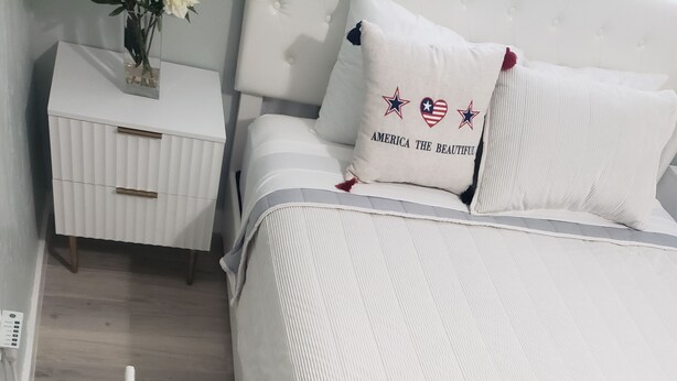 A neatly arranged bedroom with a bed, a bedside table, and a small nightstand. -  Streamlined & Chic Getaway Studio in Amazing Sarasota (Sarasota)