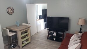 A living room with a TV, sofa, and dining area with a table and chairs. -  Streamlined & Chic Getaway Studio in Amazing Sarasota (Sarasota)