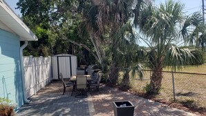 A backyard patio with a grill, outdoor table, and chairs. -  Streamlined & Chic Getaway Studio in Amazing Sarasota (Sarasota)