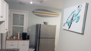 A kitchen with a stainless steel refrigerator, a microwave, a coffee maker, and a trash can. -  Streamlined & Chic Getaway Studio in Amazing Sarasota (Sarasota)
