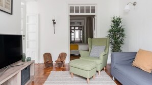 Un saló amb televisió, un butac armchair verd, un sofà blau i un armari de fusta.