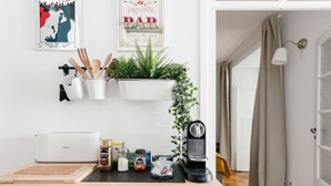 Cuina amb taulell blanc, cafetera, torradora i una planta.